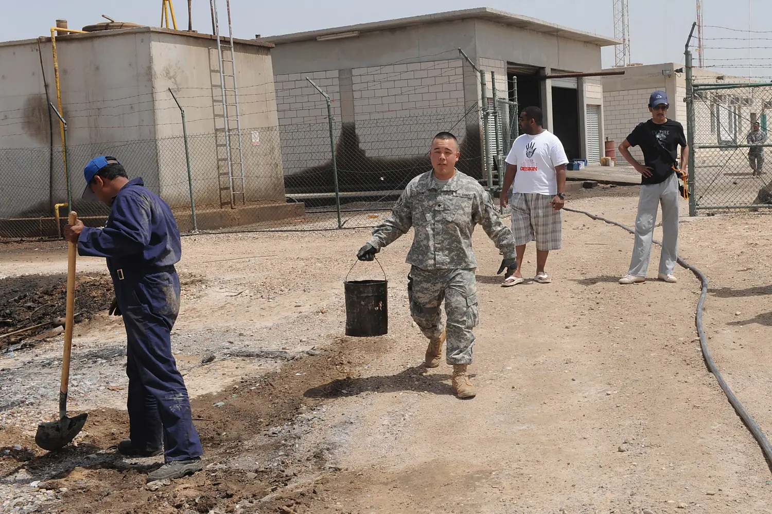 U.S. Army Spc. Ryan Soon, center left, helps residents of Warba Island, Kuwait, clean up a landing spot for a generator April 11, 2009 090411-N-QT558-016